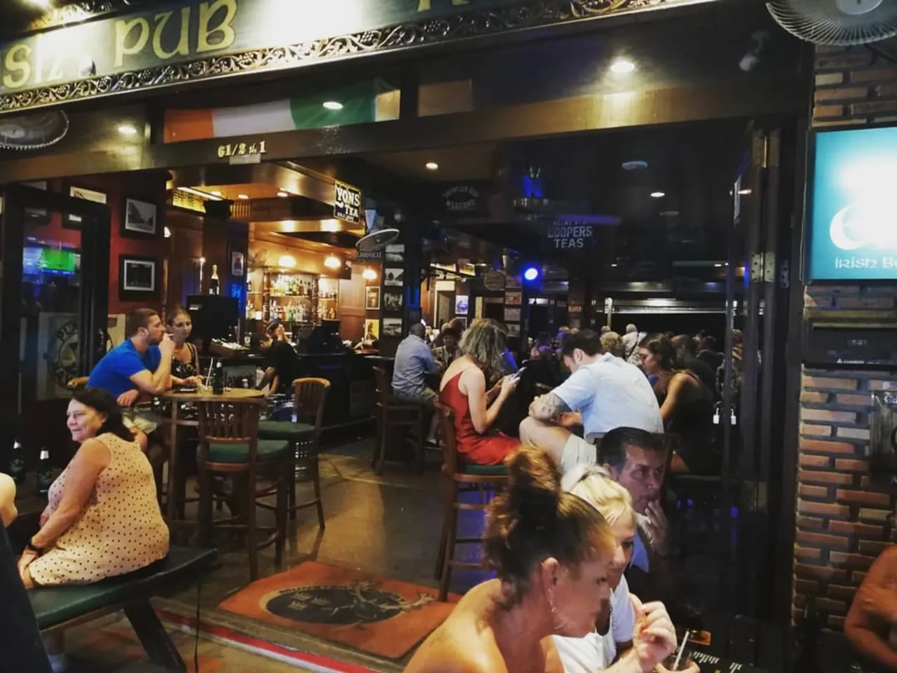 The open front of the Emerald on the Fisherman's Village street at night, with guests at tables and the bar inside